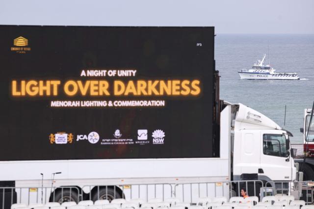 A police boat (R) patrols near a giant screen ahead of a memorial for the victims of a shooting at Bondi Beach in Sydney on December 21, 2025. (Photo by DAVID GRAY / AFP)