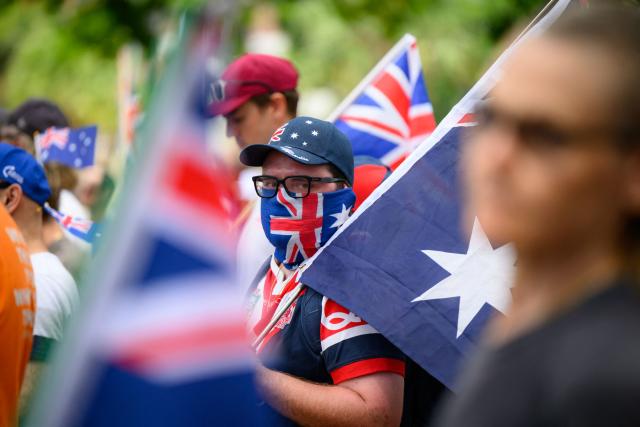 A participant masked with an Australian flag looks on during the anti-immigration 'Put Australia First' rally at Prince Alfred Park in Sydney on December 21, 2025, one week after the Bondi Beach mass shooting. (Photo by GEORGE CHAN / AFP)