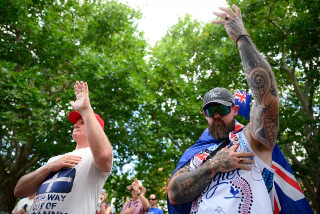 Participants mourn for victims of the Bondi Beach mass shooting during the anti-immigration 'Put Australia First' rally at Prince Alfred Park in Sydney on December 21, 2025, one week after the incident. (Photo by GEORGE CHAN / AFP)