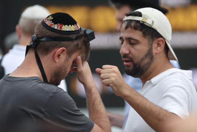 Mourners pray before the start of a memorial held for the victims of a shooting at Bondi Beach in Sydney on December 21, 2025. A father and his son are accused of spraying bullets into the family-thronged Hanukkah celebration at Sydney's most famous beach on December 14, allegedly inspired by "Islamic State ideology". (Photo by DAVID GRAY / AFP)
