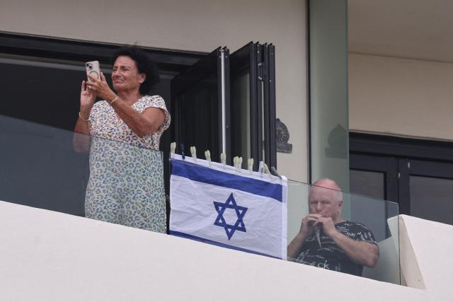 A flag of Israel is attached on a balcony of residents watching the memorial held for the victims of a shooting at Bondi Beach in Sydney on December 21, 2025. A father and his son are accused of spraying bullets into the family-thronged Hanukkah celebration at Sydney's most famous beach on December 14, allegedly inspired by "Islamic State ideology". (Photo by DAVID GRAY / AFP)