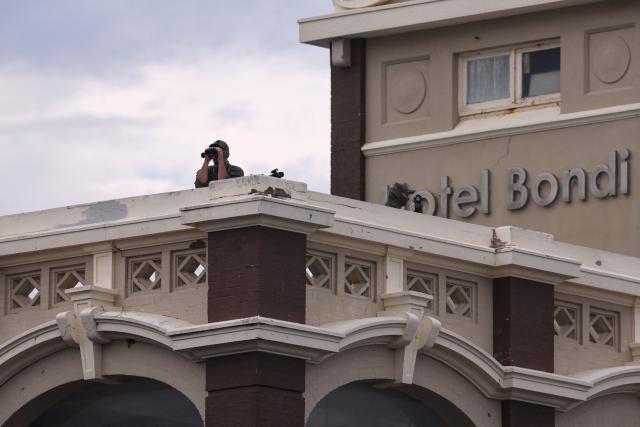 Police snipers are seen on a roof as they secure the area during the memorial held for the victims of a shooting at Bondi Beach in Sydney on December 21, 2025. A father and his son are accused of spraying bullets into the family-thronged Hanukkah celebration at Sydney's most famous beach on December 14, allegedly inspired by "Islamic State ideology". (Photo by DAVID GRAY / AFP)