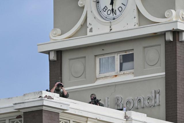 Police snipers are seen on a roof as they secure the area during the memorial held for the victims of a shooting at Bondi Beach in Sydney on December 21, 2025. A father and his son are accused of spraying bullets into the family-thronged Hanukkah celebration at Sydney's most famous beach on December 14, allegedly inspired by "Islamic State ideology". (Photo by Saeed KHAN / AFP)