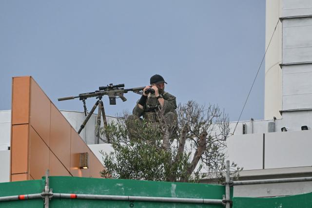 A police sniper is seen on a roof as he secures the area during the memorial held for the victims of a shooting at Bondi Beach in Sydney on December 21, 2025. A father and his son are accused of spraying bullets into the family-thronged Hanukkah celebration at Sydney's most famous beach on December 14, allegedly inspired by "Islamic State ideology". (Photo by Saeed KHAN / AFP)