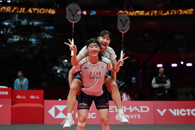 South Korea’s Baek Ha-na (top) and Lee So-hee celebrate after defeating Japan’s Yuki Fukushima and Mayu Matsumoto during their women’s doubles final match at the BWF Badminton World Tour Finals at the Hangzhou Olympic Sports Centre Gymnasium in Hangzhou, in eastern China's Zhejiang province on December 21, 2025. (Photo by Jade Gao / AFP)