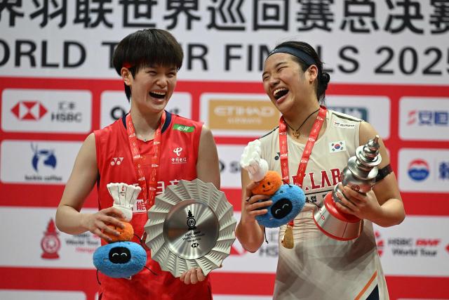 Gold medallist South Korea’s An Se-young (R) and silver medallist China’s Wang Zhiyi pose with the trophies during the award ceremony for women’s singles final match at the BWF Badminton World Tour Finals at the Hangzhou Olympic Sports Centre Gymnasium in Hangzhou, in eastern China's Zhejiang province on December 21, 2025. (Photo by Jade Gao / AFP)