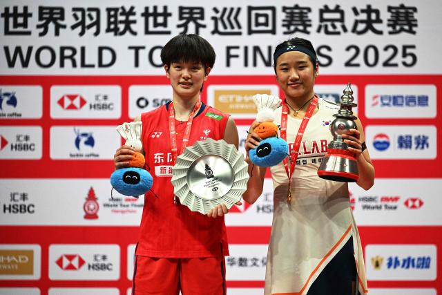 Gold medallist South Korea’s An Se-young (R), silver medallist China’s Wang Zhiyi pose with the trophies during the award ceremony for women’s singles final match at the BWF Badminton World Tour Finals at the Hangzhou Olympic Sports Centre Gymnasium in Hangzhou, in eastern China's Zhejiang province on December 21, 2025. (Photo by Jade Gao / AFP)