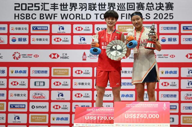 Gold medallist South Korea’s An Se-young (R), silver medallist China’s Wang Zhiyi pose with the trophies during the award ceremony for women’s singles final match at the BWF Badminton World Tour Finals at the Hangzhou Olympic Sports Centre Gymnasium in Hangzhou, in eastern China's Zhejiang province on December 21, 2025. (Photo by Jade Gao / AFP)