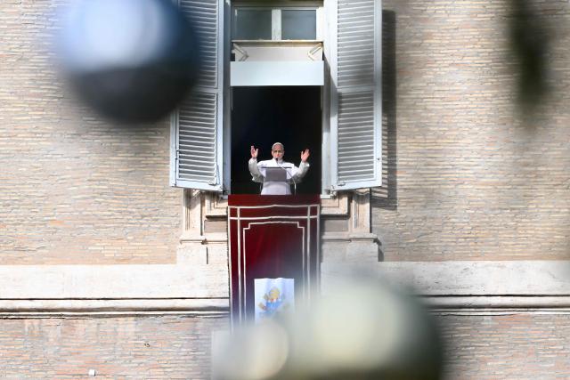 Pope Leo XIV is seen through a Chrismas tree as he addresses the crowd from a window of the apostolic palace overlooking St. Peter's Square during the Angelus prayer in The Vatican on December 21, 2025. (Photo by Andreas SOLARO / AFP)