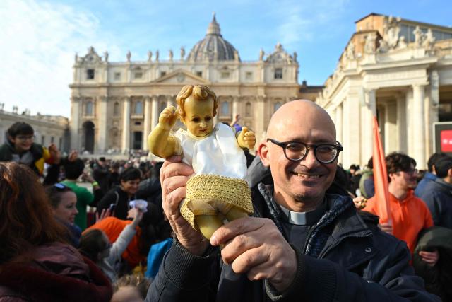 A priest holds a Nativity Scene figurine of baby Jesus before the traditional blessing of figurines as part of the pope's Sunday Angelus prayer before Christmas in Saint Peter's Square in the Vatican on December 21, 2025. (Photo by Andreas SOLARO / AFP)