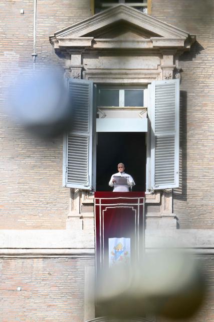 Pope Leo XIV is seen trough a Christmas tree as he addresses the crowd from a window of the apostolic palace overlooking St. Peter's Square during the Angelus prayer in The Vatican on December 21, 2025. (Photo by Andreas SOLARO / AFP)