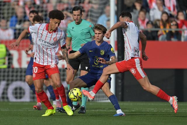 Girona's Belgian defender #20 Axel Witsel (L) and Atletico Madrid's Spanish midfielder #08 Pablo Barrios (C) fight for the ball during the Spanish league football match between Girona FC and Club Atletico de Madrid at Montilivi Stadium in Girona on December 21, 2025. (Photo by MANAURE QUINTERO / AFP)