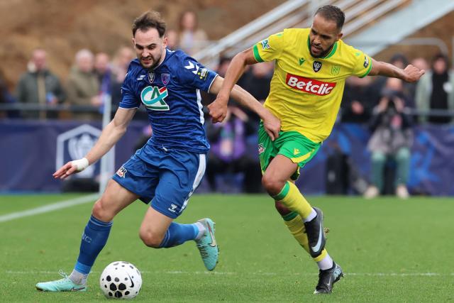 Concarneau's French defender #05 Baptiste Etcheverria fights for the ball with Nantes' Moroccan forward #9 Youssef El-Arabi during the French Cup round of 64 football match between Concarneau and Nantes at the Guy-Piriou Stadium in Concarneau, western France on December 21, 2025. (Photo by Fred TANNEAU / AFP)