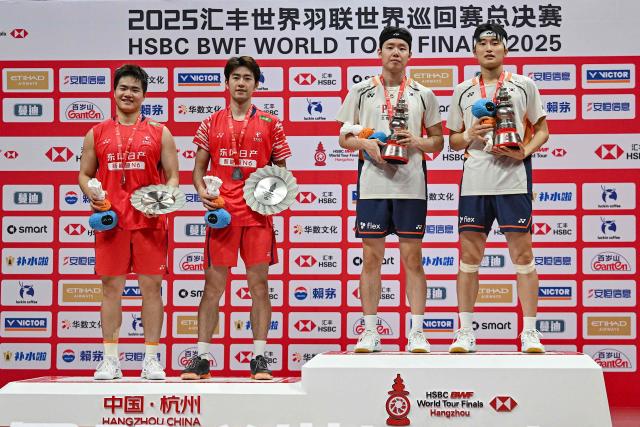 Gold medallists South Korea’s Kim Won-ho (R) and Seo Seung-Jae (2R) pose with their trophies alongside silver medallists China’s Wang Chang (2L) and Liang Weikeng during the award ceremony for the men’s doubles final match at the BWF Badminton World Tour Finals in the Hangzhou Olympic Sports Centre Gymnasium, Hangzhou, in eastern China's Zhejiang province on December 21, 2025. (Photo by Jade Gao / AFP)