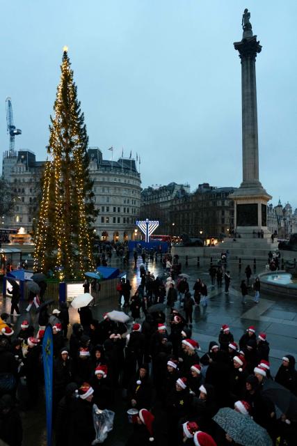 Carol singers perform around the Christmas tree in Trafalgar Square in central London on December 21, 2025. Retail sales in Britain dipped unexpectedly in November as shoppers remained cautious in the run-up to Christmas, according to official figures. (Photo by CARLOS JASSO / AFP)