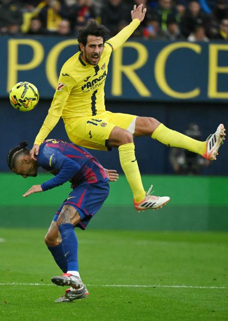 Barcelona's Brazilian forward #11 Raphinha (L) and Villarreal's Spanish midfielder #10 Daniel Parejo fight for the ball during the Spanish league football match between Villarreal CF and FC Barcelona at La Ceramica Stadium in Vila-real on December 21, 2025. (Photo by JOSE JORDAN / AFP)
