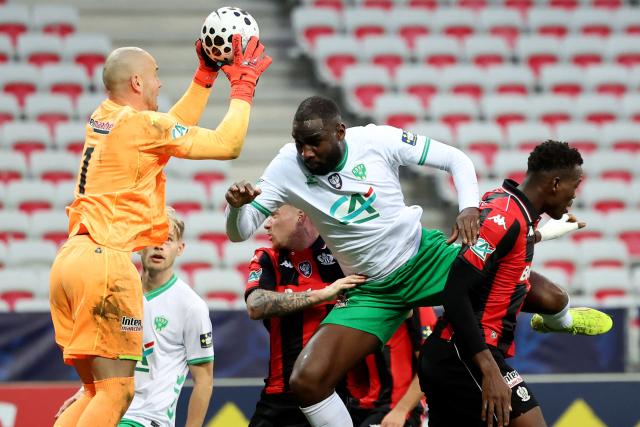 Nice's French goalkeeper #31 Maxime Dupé (L) grabs the ball in front of Saint Etienne's Mickael Nade (C) during the French Cup round of 64 football match between OGC Nice and Saint-Etienne at the Allianz Riviera Stadium in Nice, south-eastern France, on December 21, 2025. (Photo by Valery HACHE / AFP)