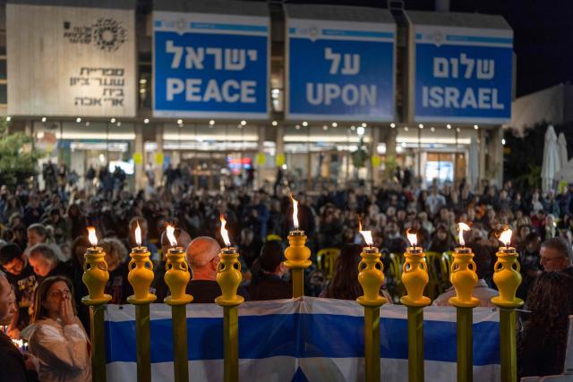Israelis light the 8th candle of Hannukah in Hostage Square, in Tel Aviv on December 21, 2025, as they call for the return Ran Gvili's remains. Of the 251 people taken hostage during Hamas's unprecedented October 7, 2023 attack that sparked the war in Gaza, all but the remains of Israeli Ran Gvili have been handed over. (Photo by ILIA YEFIMOVICH / AFP)