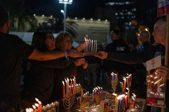 Israelis light the 8th candle of Hannukah in Hostage Square, in Tel Aviv on December 21, 2025, as they call for the return Ran Gvili's remains. Of the 251 people taken hostage during Hamas's unprecedented October 7, 2023 attack that sparked the war in Gaza, all but the remains of Israeli Ran Gvili have been handed over. (Photo by ILIA YEFIMOVICH / AFP)