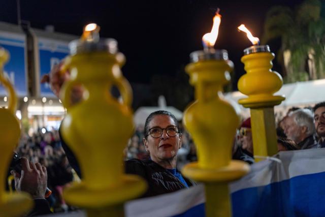 TOPSHOT - Talik Gvili, mother of a hostage Ran Gvili, lights a candle as Israelis light the 8th candle of Hannukah in Hostage Square in Tel Aviv on December 21, 2025, as they call for the return her son's remains. Of the 251 people taken hostage during Hamas's unprecedented October 7, 2023 attack that sparked the war in Gaza, all but the remains of Israeli Ran Gvili have been handed over. (Photo by ILIA YEFIMOVICH / AFP)