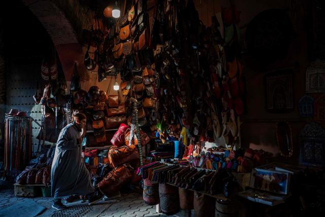 TOPSHOT - Moroccan shop owner of leather goods walks in front of his store in the old market of Marrakech city on December 21, 2025, during the Africa Cup of Nations (CAN) football tournament. (Photo by Khaled DESOUKI / AFP)