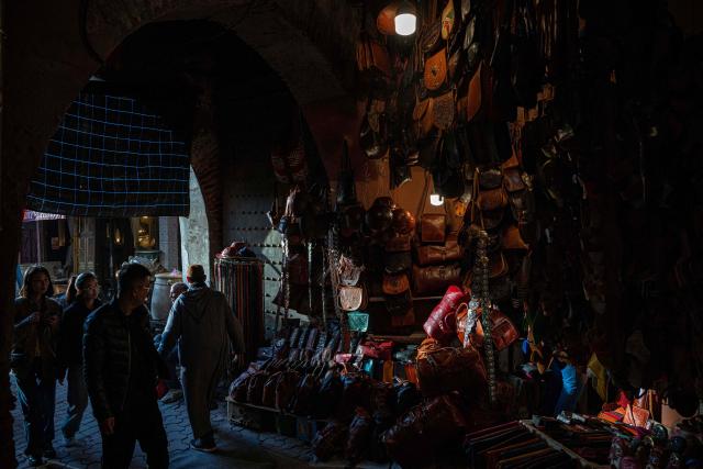 Tourists pass by a shop display leather goods display in the old market of Marrakech city on December 21, 2025, during the Africa Cup of Nations (CAN) football tournament. (Photo by Khaled DESOUKI / AFP)