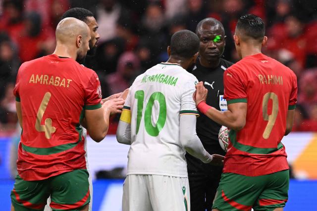 Comoros's midfielder #10 Youssouf M'Changama and Morocco's forward #09 Soufiane Rahimi argue with referee Jean-Jacques Ngambo Ndala during the Africa Cup of Nations (CAN) group A  football match between Morocco and Comoros at Prince Moulay Abdellah Stadium in Rabat on December 21, 2025. (Photo by SEBASTIEN BOZON / AFP)