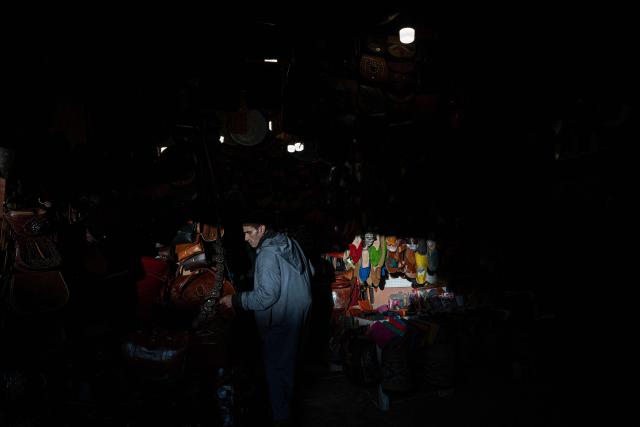 Moroccan shop owner of leather goods arranges his merchandise at the store in the old market of Marrakech city on December 21, 2025, during the Africa Cup of Nations (CAN) football tournament. (Photo by Khaled DESOUKI / AFP)