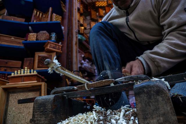 A Moroccan craftsman makes a rosary from wood in his shop at the old market of Marrakech city on December 21, 2025, during the Africa Cup of Nations (CAN) football tournament. (Photo by Khaled DESOUKI / AFP)