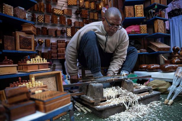 A Moroccan craftsman makes a rosary from wood in his shop at the old market of Marrakech city on December 21, 2025, during the Africa Cup of Nations (CAN) football tournament. (Photo by Khaled DESOUKI / AFP)