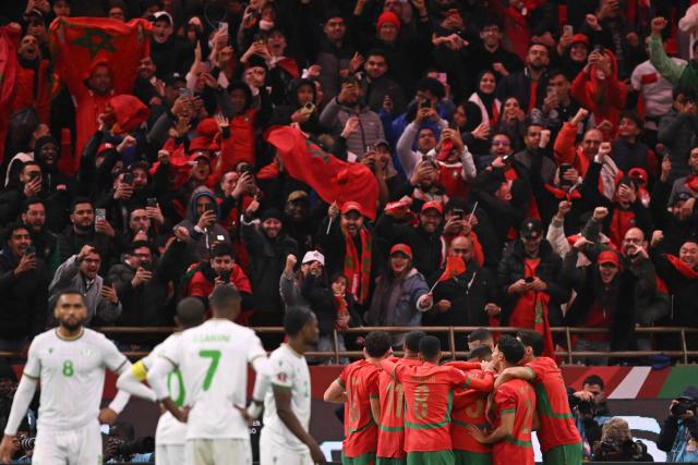 Morocco's forward #10 Brahim Diaz (hidden) celebrates scoring his team's first goal with teammates during the Africa Cup of Nations (CAN) group A  football match between Morocco and Comoros at Prince Moulay Abdellah Stadium in Rabat on December 21, 2025. (Photo by SEBASTIEN BOZON / AFP)