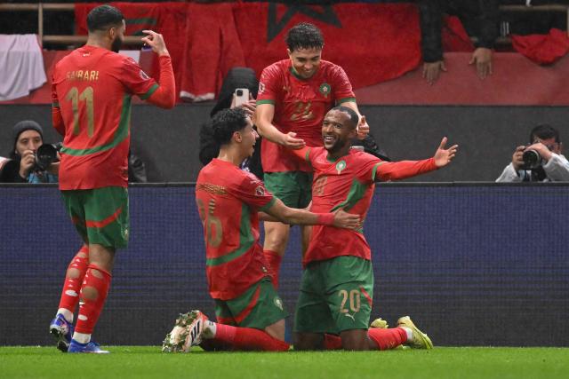 Morocco's forward #20 Ayoub El Kaabi celebrates with teammates after scoring his team's second goal during the Africa Cup of Nations (CAN) group A  football match between Morocco and Comoros at Prince Moulay Abdellah Stadium in Rabat on December 21, 2025. (Photo by SEBASTIEN BOZON / AFP)