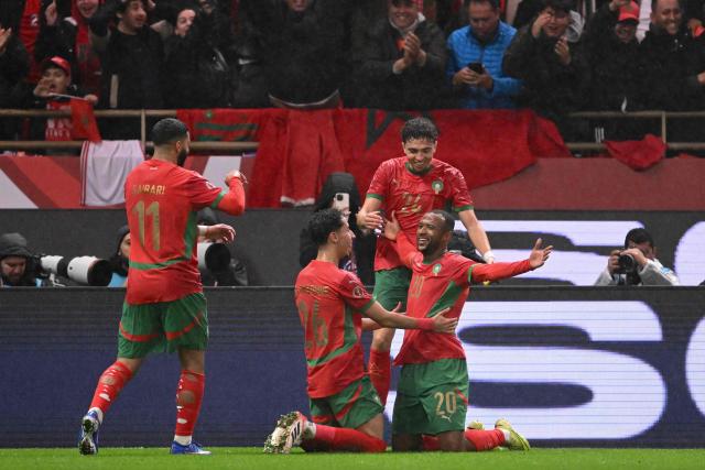 Morocco's forward #20 Ayoub El Kaabi celebrates with teammates after scoring his team's second goal during the Africa Cup of Nations (CAN) group A  football match between Morocco and Comoros at Prince Moulay Abdellah Stadium in Rabat on December 21, 2025. (Photo by SEBASTIEN BOZON / AFP)