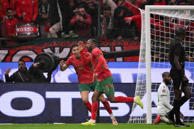 Morocco's forward #20 Ayoub El Kaabi celebrates with teammate Morocco's midfielder #24 Neil El Aynaoui scoring his team's second during the Africa Cup of Nations (CAN) group A  football match between Morocco and Comoros at Prince Moulay Abdellah Stadium in Rabat on December 21, 2025. (Photo by SEBASTIEN BOZON / AFP)