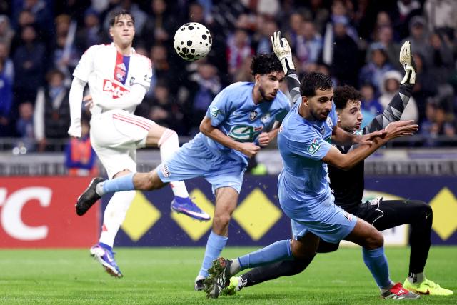 FC Saint-Cyr Collonges French defender Foudil Bakhtia (2nd-R) and FC Saint-Cyr Collonges French goalkeeper Mehdi Chakri (R) save the ball on their goal line during the French Cup round of 64 football match between - Olympique Lyonnais (OL) and Saint-Cyr-Collonges at the Groupama Stadium in Lyon, south eastern France on December 21, 2025. (Photo by Alex MARTIN / AFP)