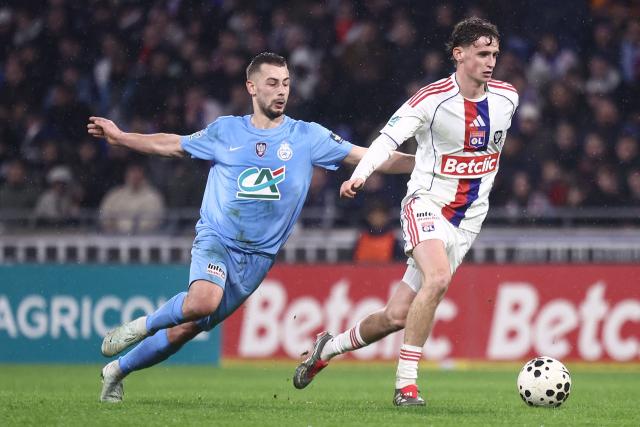 FC Saint-Cyr Collonges French midfielder Arnaud Braillon (L) vies with Lyon's British midfielder Tyler Morton  (R) during the French Cup round of 64 football match between Olympique Lyonnais (OL) and Saint-Cyr-Collonges at the Groupama Stadium in Lyon, south eastern France on December 21, 2025. (Photo by Alex MARTIN / AFP)