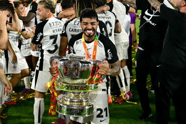 Corinthians' defender #21 Matheus Bidu celebrates with the trophy of the Brazil Cup after the final second leg football match between Vasco da Gama and Corinthians at the Maracana stadium in Rio de Janeiro, Brazil on December 21, 2025. (Photo by Pablo PORCIUNCULA / AFP)