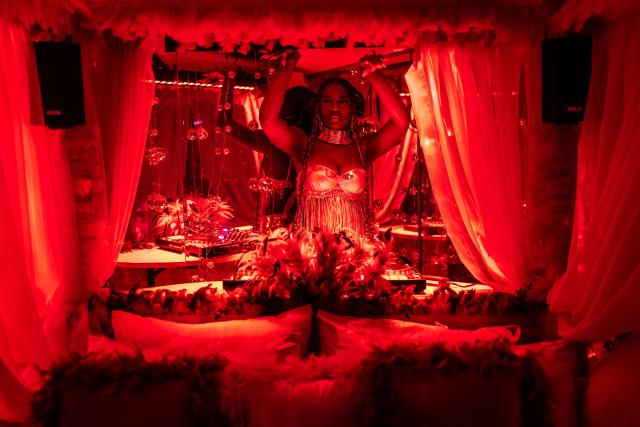 A DJ performs next to a bed in a decorated selfie space inside the restroom of the Lulu beach club during its opening during “Detty December” in Lagos on November 21, 2025. “Detty December” refers to the lively Lagos tradition where December is packed with nonstop parties, concerts, nightlife, and cultural events, fuelled by returning diaspora Nigerians and heightened local celebration. The city becomes especially vibrant and crowded as entertainment and tourism peak. The spelling “detty” comes from Nigerian Pidgin English, where it is a playful version of “dirty” that implies excess, intensity, and carefree fun. (Photo by OLYMPIA DE MAISMONT / AFP)