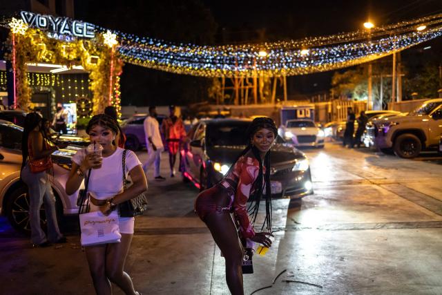 A patron poses for a photograph in the parking lot of the Voyage nightclub during “Detty December” in Ikeja, Lagos, on December 7, 2025. “Detty December” refers to the lively Lagos tradition where December is packed with nonstop parties, concerts, nightlife, and cultural events, fuelled by returning diaspora Nigerians and heightened local celebration. The city becomes especially vibrant and crowded as entertainment and tourism peak. The spelling “detty” comes from Nigerian Pidgin English, where it is a playful version of “dirty” that implies excess, intensity, and carefree fun. (Photo by OLYMPIA DE MAISMONT / AFP)