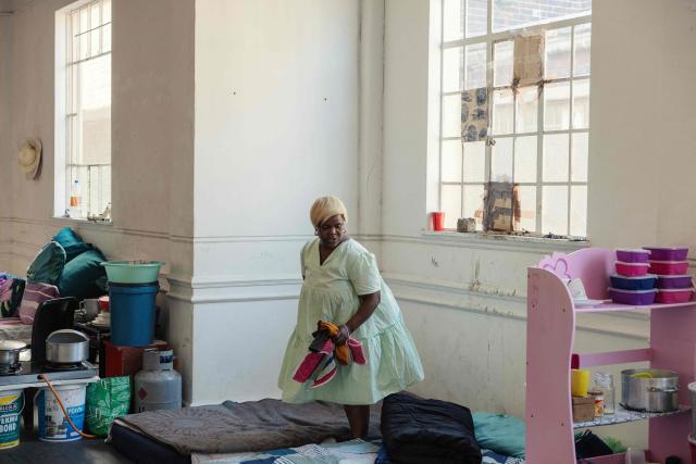A resident goes through her belongings in one of the halls of an occupied building in downtown Cape Town on December 18, 2025. Nestled between spectacular mountains and the Atlantic Ocean, Cape Town has emerged as a growing tourism destination, topping in 2025 the Telegraph and Time Out magazine's rankings of best cities in the world. 
Activists say the drive to profit from tourism accommodation is pricing locals out of coveted neighbourhoods, including areas near District Six -- a site long associated with the apartheid-era removals that displaced non-white communities to remote, underdeveloped townships. (Photo by GIANLUIGI GUERCIA / AFP)