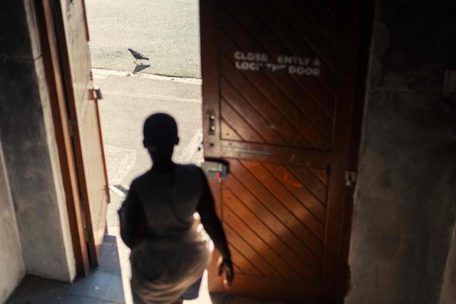 A resident leaves an occupied building in downtown Cape Town on December 18, 2025. Nestled between spectacular mountains and the Atlantic Ocean, Cape Town has emerged as a growing tourism destination, topping in 2025 the Telegraph and Time Out magazine's rankings of best cities in the world. 
Activists say the drive to profit from tourism accommodation is pricing locals out of coveted neighbourhoods, including areas near District Six -- a site long associated with the apartheid-era removals that displaced non-white communities to remote, underdeveloped townships. (Photo by GIANLUIGI GUERCIA / AFP)