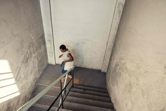 A resident leaves an occupied building in downtown Cape Town on December 18, 2025. Nestled between spectacular mountains and the Atlantic Ocean, Cape Town has emerged as a growing tourism destination, topping in 2025 the Telegraph and Time Out magazine's rankings of best cities in the world. 
Activists say the drive to profit from tourism accommodation is pricing locals out of coveted neighbourhoods, including areas near District Six -- a site long associated with the apartheid-era removals that displaced non-white communities to remote, underdeveloped townships. (Photo by GIANLUIGI GUERCIA / AFP)