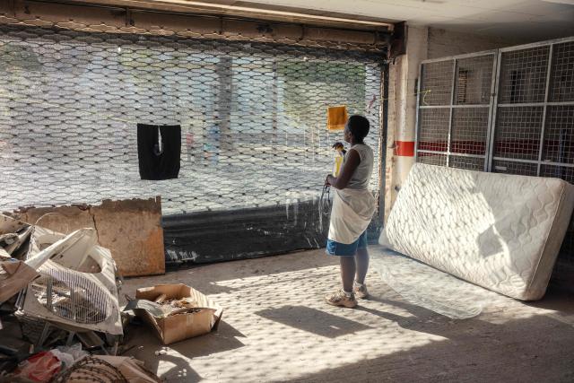 A resident looks out from a garage entrance of an occupied building in downtown Cape Town on December 18, 2025. Nestled between spectacular mountains and the Atlantic Ocean, Cape Town has emerged as a growing tourism destination, topping in 2025 the Telegraph and Time Out magazine's rankings of best cities in the world. 
Activists say the drive to profit from tourism accommodation is pricing locals out of coveted neighbourhoods, including areas near District Six -- a site long associated with the apartheid-era removals that displaced non-white communities to remote, underdeveloped townships. (Photo by GIANLUIGI GUERCIA / AFP)