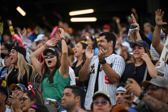 Baseball fans cheer during the baseball game between Navegantes del Magallanes and Leones del Caracas at the Simon Bolivar Monumental Stadium in Caracas, on December 21, 2025. (Photo by Federico PARRA / AFP)