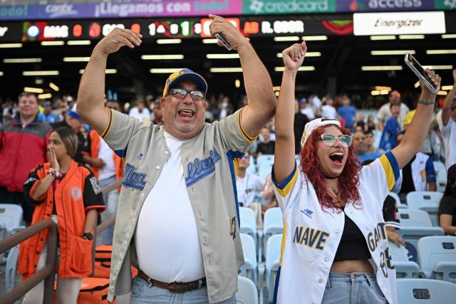 Fans of Navegantes del Magallanes cheer for their team during the baseball game between Navegantes del Magallanes and Leones del Caracas at the Simon Bolivar Monumental Stadium in Caracas, on December 21, 2025. (Photo by Federico PARRA / AFP)