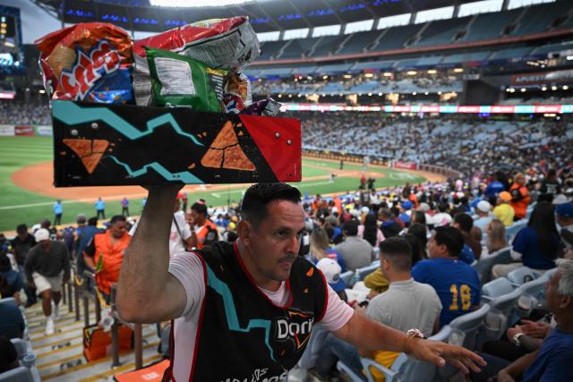 A man sells snacks during the baseball game between Navegantes del Magallanes and Leones del Caracas at the Simon Bolivar Monumental Stadium in Caracas, on December 21, 2025. (Photo by Federico PARRA / AFP)