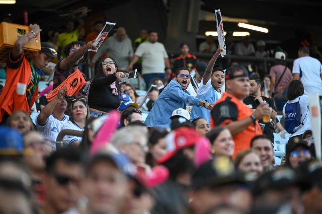 Baseball fans cheer during the baseball game between Navegantes del Magallanes and Leones del Caracas at the Simon Bolivar Monumental Stadium in Caracas, on December 21, 2025. (Photo by Federico PARRA / AFP)