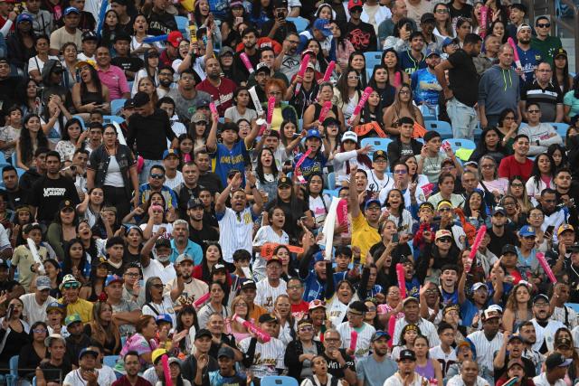 Fans cheer during the baseball game between Navegantes del Magallanes and Leones del Caracas at the Simon Bolivar Monumental Stadium in Caracas, on December 21, 2025. (Photo by Federico PARRA / AFP)