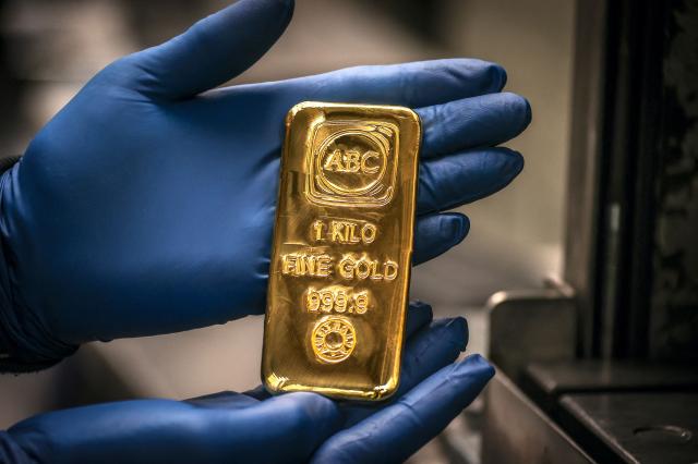(FILES) A worker displays a one kilogram gold bullion bar at the ABC Refinery in Sydney on August 5, 2020. Gold prices shot to a record high on December 22, 2025 as investors grow increasingly optimistic the US Federal Reserve will continue to cut interest rates through next year. (Photo by DAVID GRAY / AFP)