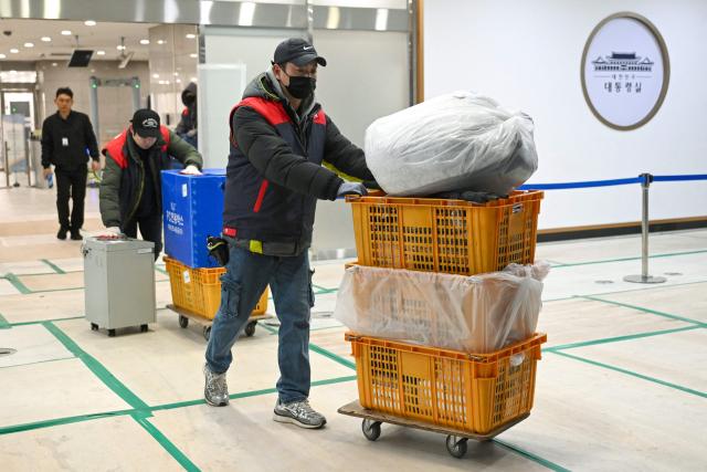 Workers carry boxes at the Presidential Office in Seoul on December 22, 2025, as South Korea's presidential office is moved back to the Blue House. South Korea's president and his team have started moving back into Seoul's historic Blue House and the process will be wrapped up by Christmas, an official said on December 9. (Photo by Jung Yeon-je / AFP)